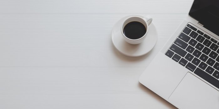 Ein Tisch auf dem eine Tasse Kaffe und ein ein teil eines Laptops